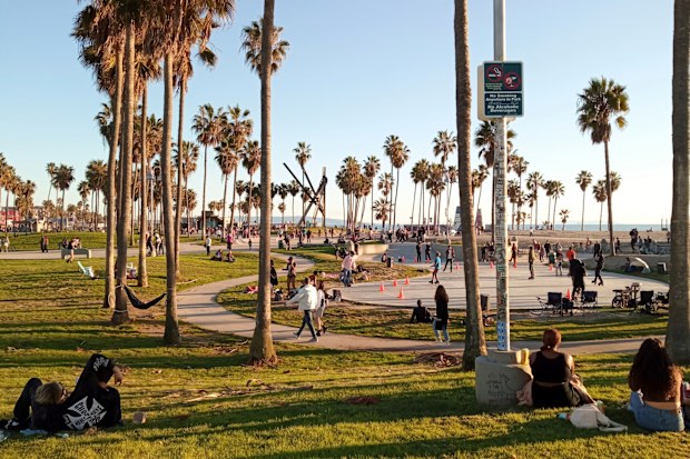 People enjoy a sunny day at Venice Beach Oceanfront Walk in Los Angeles, California. 