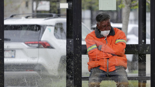 A man sits at a bus stop while wearing a face mask in Wheeling, Illinois.