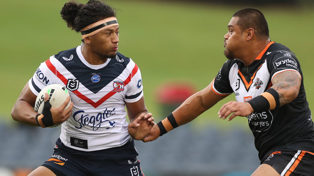Wests Tigers centre Joey Leilua tries to take down Roosters forward Sitili Tupouniua.