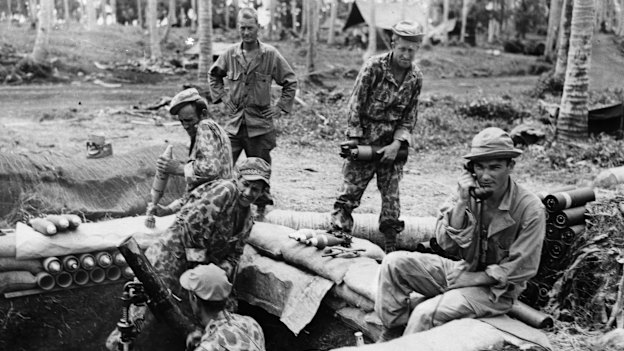 During World War II, soldiers fire a camouflaged gun during a barrage in the Solomon Islands.