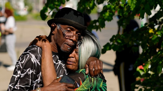 People embrace outside the scene of a shooting at a supermarket a day earlier, in Buffalo, New York. 