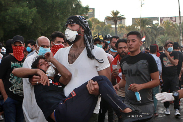 An injured protester is rushed to a hospital during a demonstration in Baghdad, Iraq, on Saturday. Protesters converged on a central square as security forces erected blast walls to prevent them from reaching a heavily fortified government area after a day of violence that killed scores.