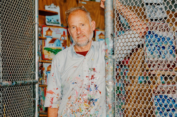 Steve Keene in his home workspace, a studio encircled in chain-link fencing that he affectionately calls “The Cage”.
