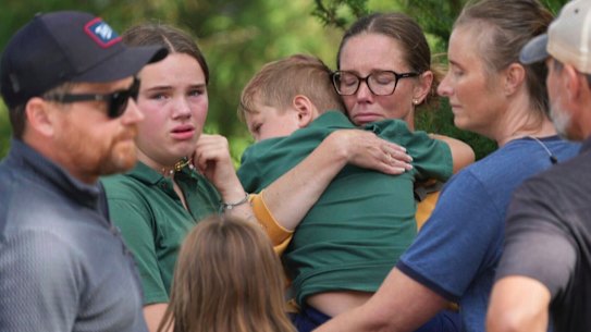 Parents comfort their children after the deadly shooting at Annunciation Church in Minneapolis in Wednesday.