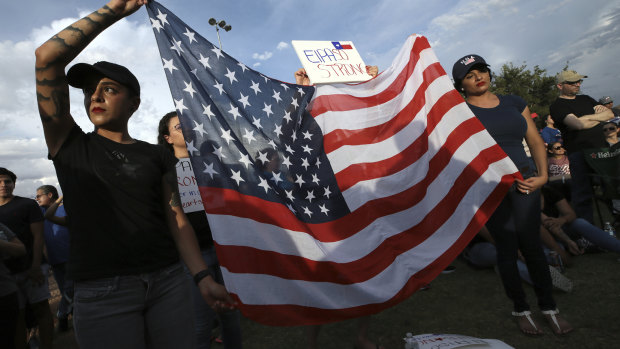 Twin sisters Jessica Torres, left, and Danielle Novoa hold an American flag during the Hope Border Institute prayer vigil for the victims of Saturday's mass shooting at a shopping complex in El Paso, Texas.