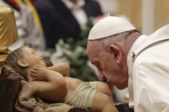 Pope Francis kisses a statue of Baby Jesus during Christmas Eve Mass.