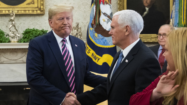 US President Donald Trump, left, shakes hands with Vice President Mike Pence during a meeting in the Oval Office a day after he was impeached.