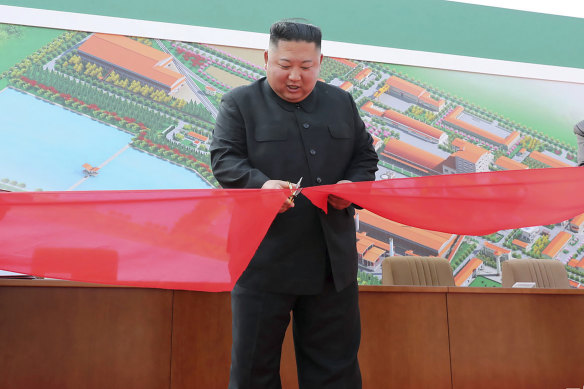 Kim Jong-un, centre, cuts a ribbon during his visit to a fertiliser factory in South Pyongan on Friday.