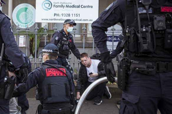 A bloodied anti-lockdown protester is detained by police after a scuffle on Victoria Street in North Melbourne.