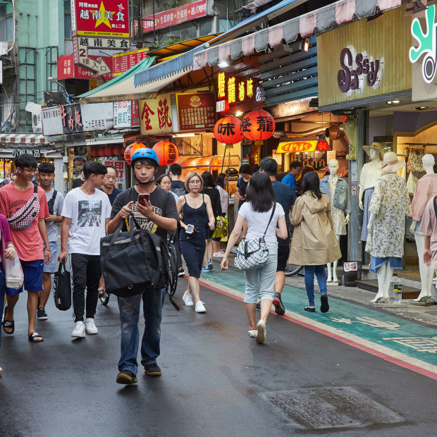 Tourists and locals walk around a night market in Taipei in 2018.