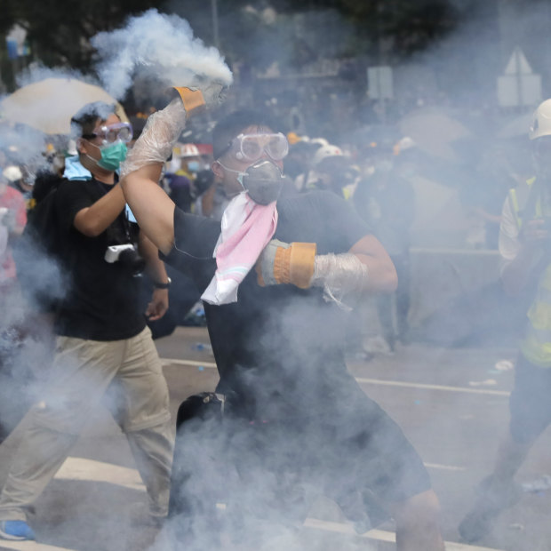 A demonstrator throws a canister of tear gas back at police during protests outside the Legislative Council on June 12.