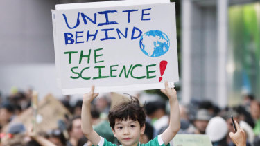 A boy holds up a placard while joining a rally, calling for action to guard against climate change in Tokyo on Friday.