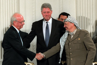 President Bill Clinton, centre, looks on as Israeli Prime Minister Yitzhak Rabin, left, and PLO leader Yasser Arafat shake hands in the East Room of the White House after signing the Mideast accord in Washington on Sept. 28, 1995.