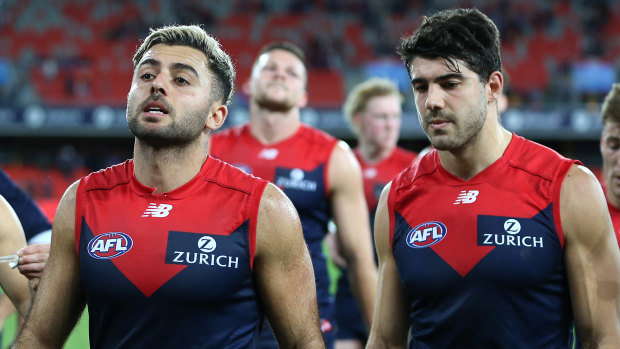 Near miss: Christian Salem and Christian Petracca walk off with their dejected Demons teammates after the narrow loss to the Lions.