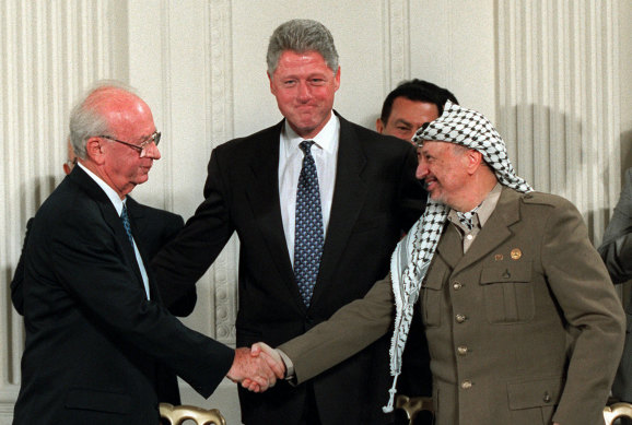 President Bill Clinton, centre, looks on as Israeli Prime Minister Yitzhak Rabin, left, and PLO leader Yasser Arafat shake hands in the East Room of the White House after signing the Mideast accord in Washington on Sept. 28, 1995.