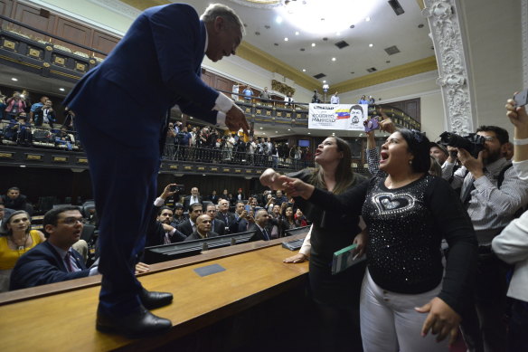 Opposition lawmaker William Barrientos stands on a desk to argue with ruling party lawmakers after his political allies were blocked from entering parliament.