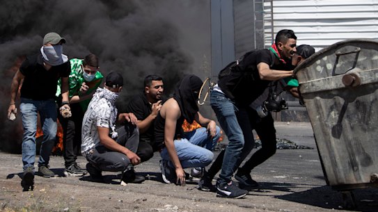 Palestinian demonstrators take cover during clashes with Israeli forces at the Hawara checkpoint, south of the West Bank city of Nablus, on Friday.