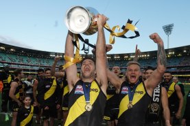 Trent Cotchin holds the premiership trophy aloft as the Tigers leave the field after winning the 2019 grand final.