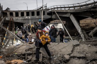 Residents of Irpin fleeing heavy fighting via a destroyed bridge as Russian forces enter the city on Monday.