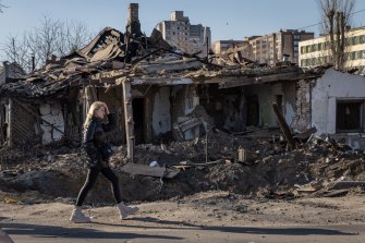 A woman walks past a rocket crater and a former home that was damaged in a recent Russian attack in Zhytomyr, Ukraine.