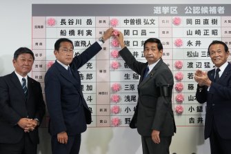 Fumio Kishida, soldan ikinci, Japonya başbakanı, partinin Tokyo'daki genel merkezinde, üst meclis seçimlerinde zaferi belirtmek için bir LDP adayının adının üzerine kırmızı bir kağıt gül yerleştiriyor.