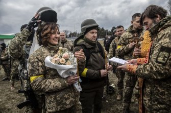 A military helmet is lifted over Filimonova at the wedding ceremony. 