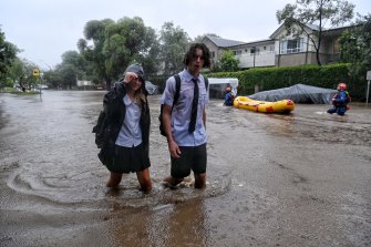 Students trudge through floodwater 
in Macpherson Street, Warriewood.
