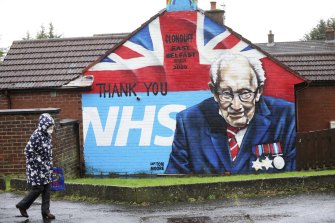 A woman walks past a mural of Captain Tom Moore in East Belfast, Northern Ireland.