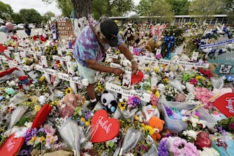 A visitor places bracelets on crosses at a memorial as he and others pay their respects to the victims killed in the Robb Elementary School shooting.
