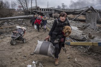 People cross an improvised path under a destroyed bridge while fleeing the town of Irpin, Ukraine.
