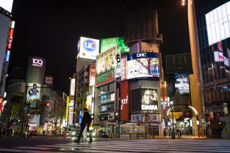 A pedestrian crosses a near-empty intersection at night in the Shibuya district of Tokyo, Japan, on April 12.