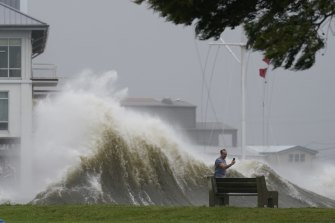 A man takes pictures of high waves along the shore of Lake Pontchartrain in Louisiana as Hurricane Ida nears.  Climate change will lift sea levels everywhere, adding more heat to the oceans.