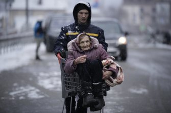 An elderly woman is carried in a shopping cart after being evacuated from Irpin, on the outskirts of Kyiv, Ukraine, on Tuesday.