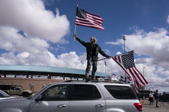 Jeff Cassil waves two American flags from the roof of his car at the beginning of The People’s Convoy to Washington DC. 