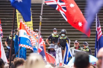 Police keep watch as protesters gather outside Parliament House on Saturday.
