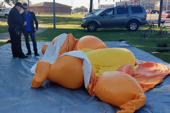A responding officer and an unidentified man stands by the deflated Baby Trump balloon that was knife in Tuscaloosa, Alabama. 