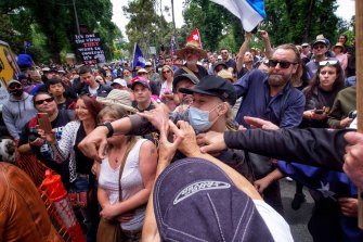 People in the crowd attempt to prevent a young man from throwing objects at Craig Kelly during the anti-vaccine mandate rally in Melbourne on Saturday.