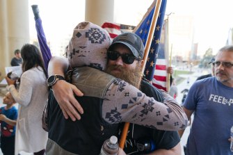Biden supporter Geoph Espen, left, hugs Trump supporter Kevin Skinner in Lansing, Michigan, after the two moderated an impromptu debate between their sides following a protest by Trump supporters over the election results.