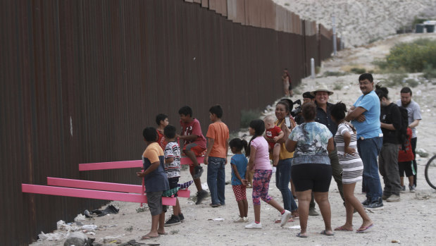 Children play on seesaws installed between the border fence at the US-Mexico border.