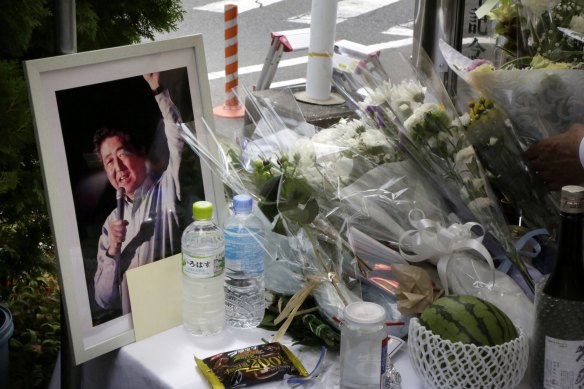 Flowers, bottles of water and a framed photograph of former Japanese prime minister Shinzo Abe rest in a makeshift shrine near the crime scene in Nara on Saturday.