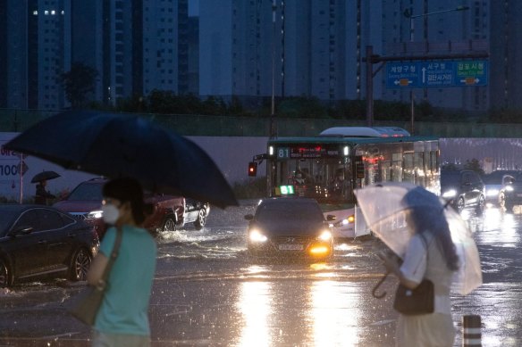 Vehicles drive through a flooded junction in Gimpo on Tuesday evening.