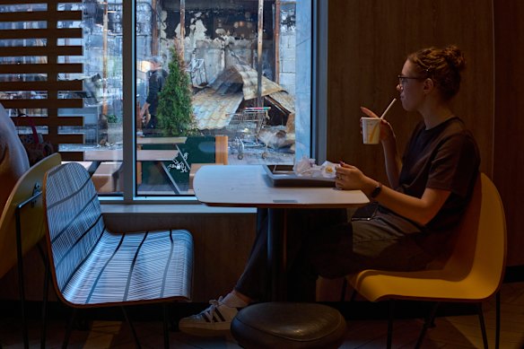 A customer in a Kyiv McDonald’s looks at a nearby office building destroyed by a Russian missile strike.