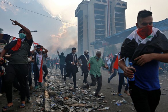 Anti-government protesters run to take cover while Iraqi security forces fire tear gas during a demonstration in Tahrir Square in Baghdad in 2019.