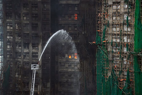 Firefighters hose down a smouldering residential building at the Wang Fuk Court.