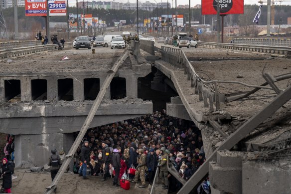 Ukrainians crowd under a destroyed bridge as they try to flee across the Irpin River in the outskirts of Kyiv, Ukraine on Saturday.