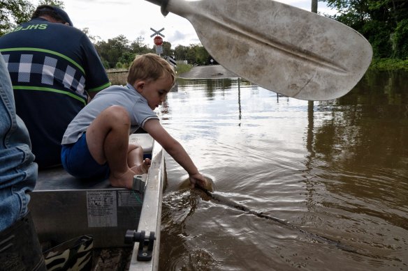 Forbes local Andrew Quirk, with Matt Robb and his child Tom Robb, float through significant floodwater earlier this month.