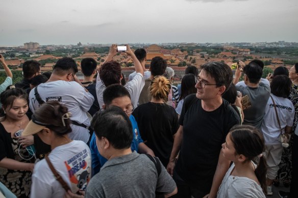 Les visiteurs se rassemblent pour voir la Cité interdite au coucher du soleil au parc Jingshan à Pékin.