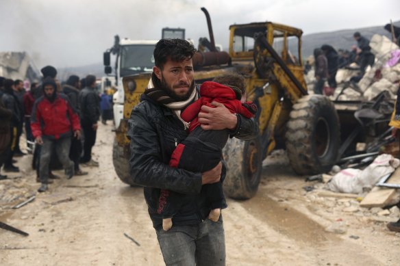 A man carries a child following the earthquake in the Besnia village near the Turkish border, Idlib province, Syria.