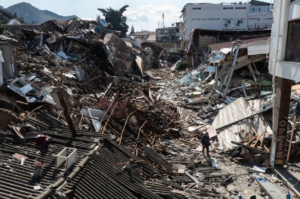 A man walks past collapsed buildings in Hatay, Turkey.