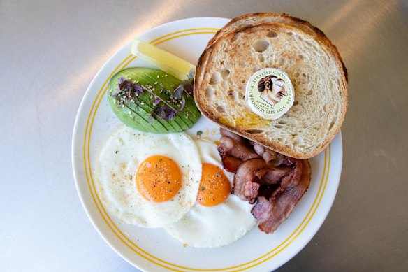 Fried eggs and toast with avocado and bacon. 